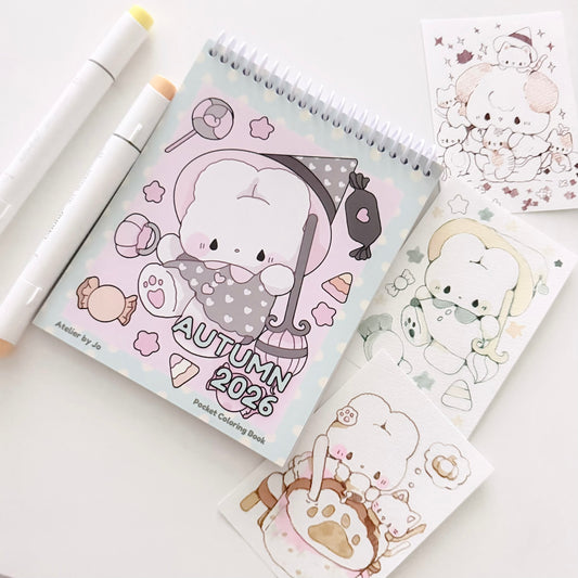 A spiral-bound pocket coloring book with a cute autumn-themed character illustration on the cover, shown on a white background with two white markers and several printed sticker sheets featuring matching cartoon artwork.