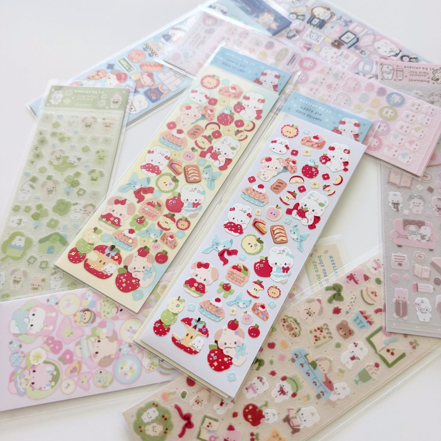 A collection of cute, pastel-colored sticker sheets featuring characters, desserts, and illustrations, arranged on a white surface.