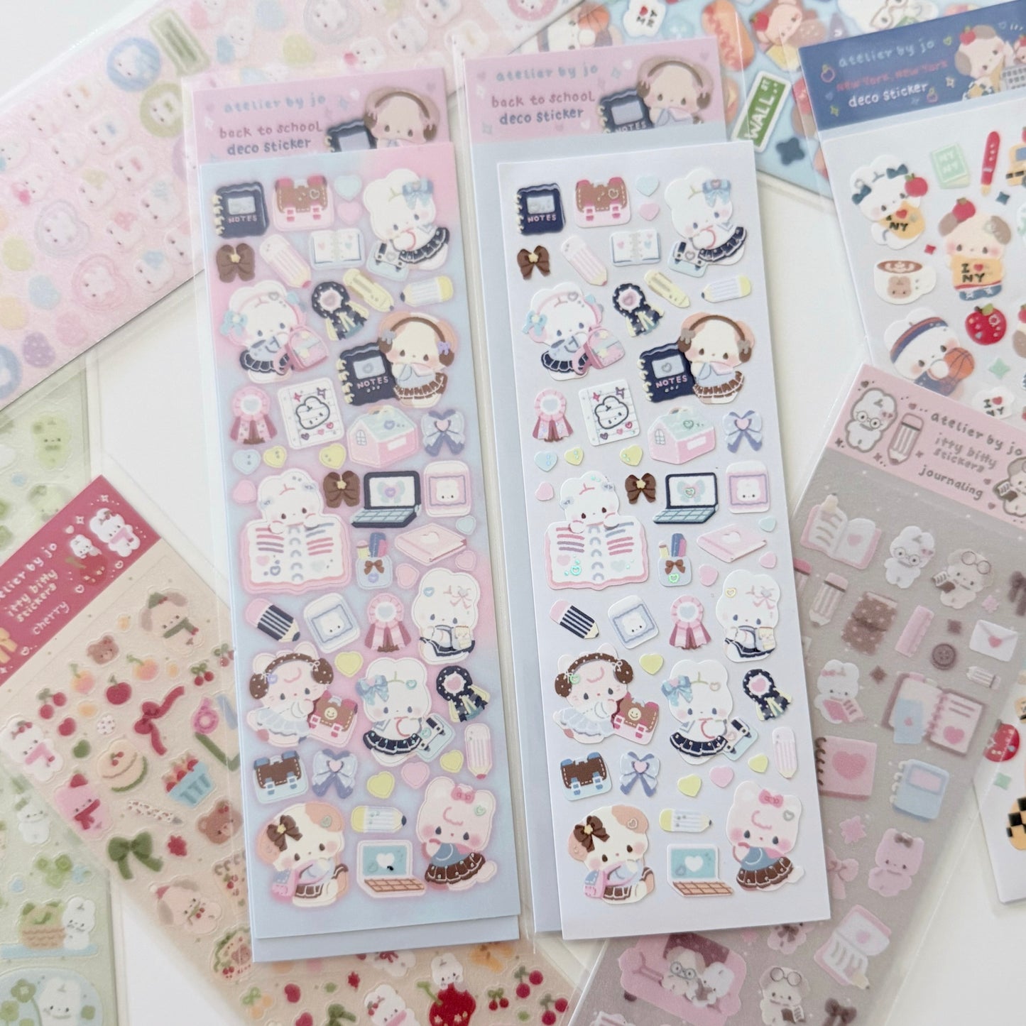 Several sheets of cute planner stickers featuring cartoon animals, school supplies, and pastel illustrations arranged on a light surface.