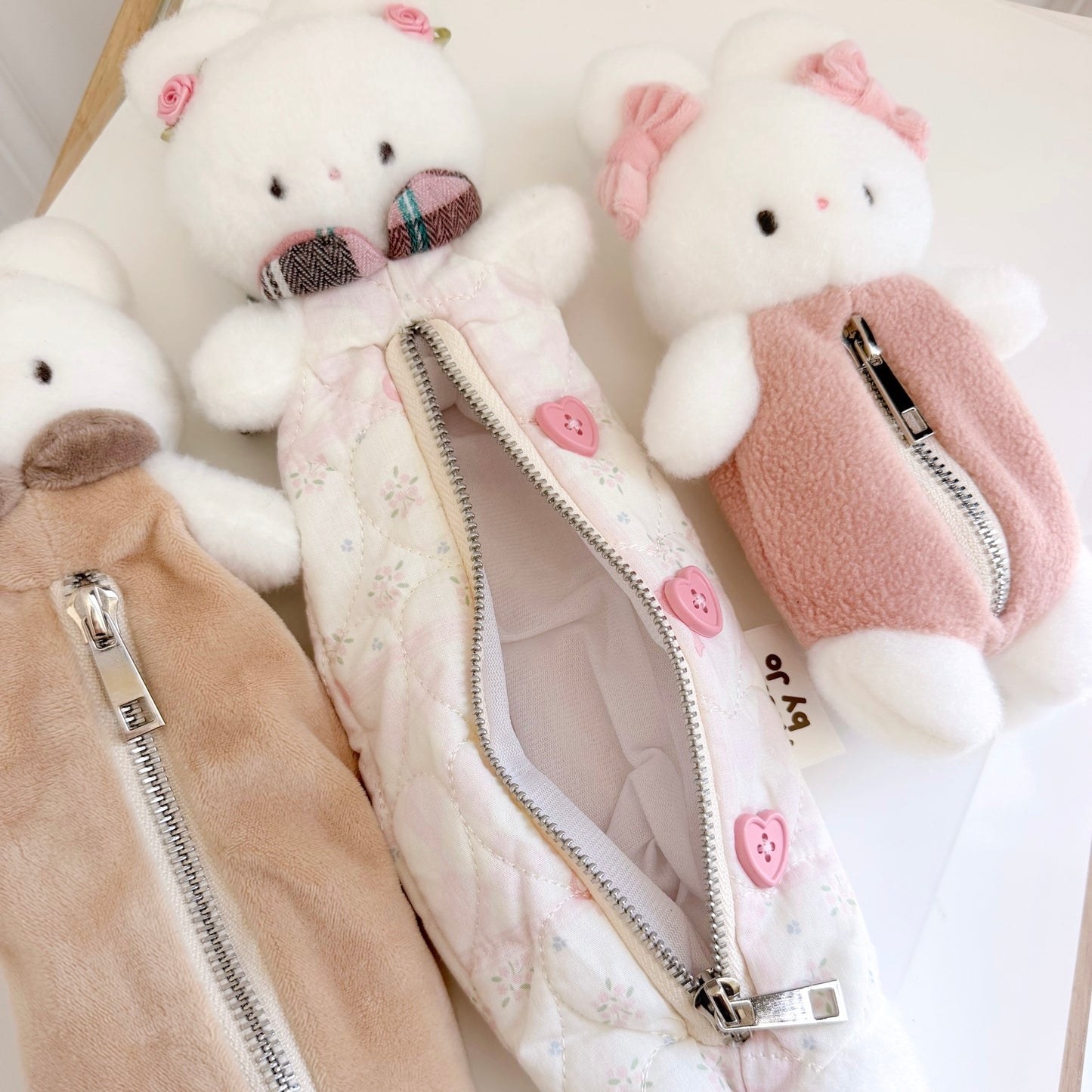 Three differently sized multicolored bunny pouches on white surface