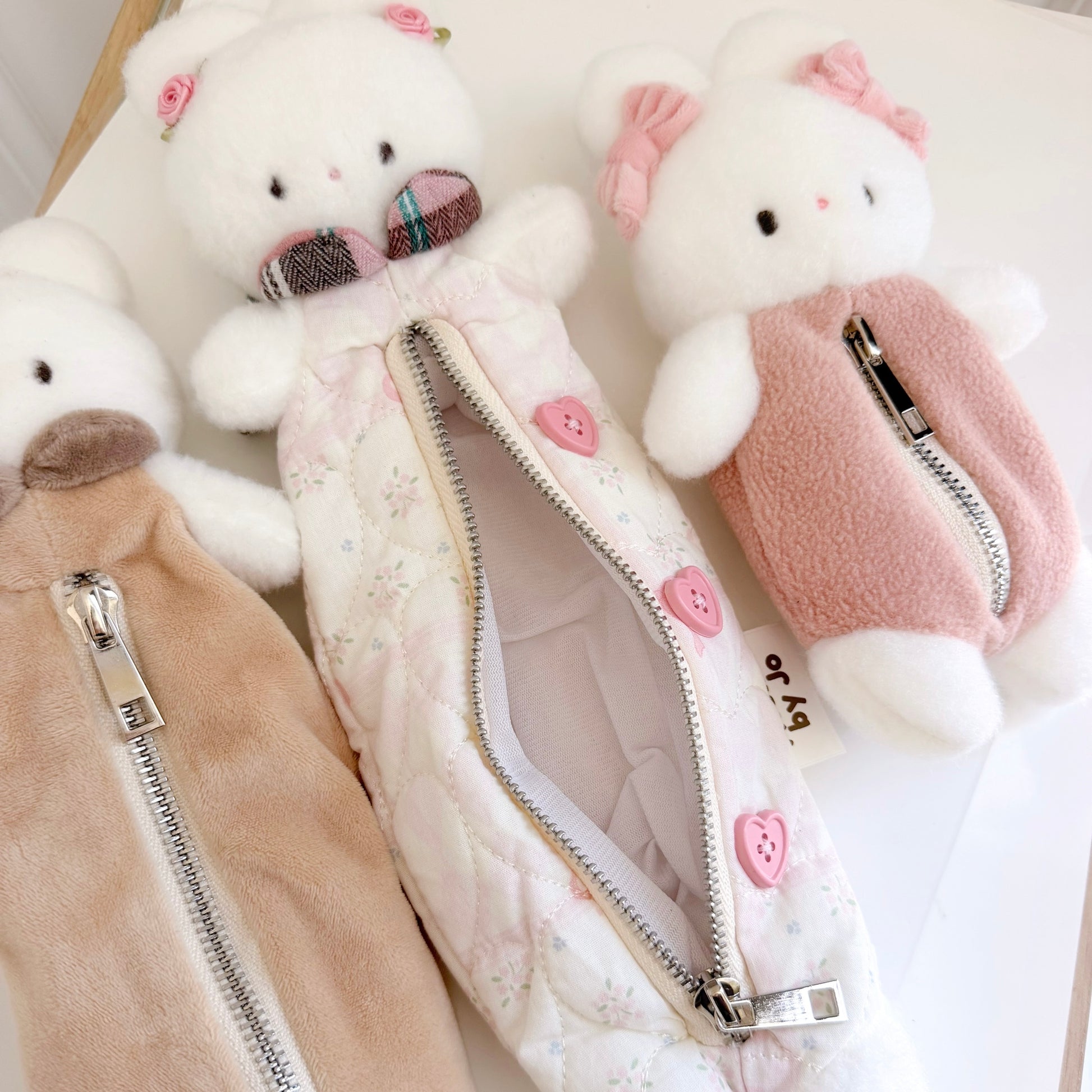 Three differently sized multicolored bunny pouches on white surface
