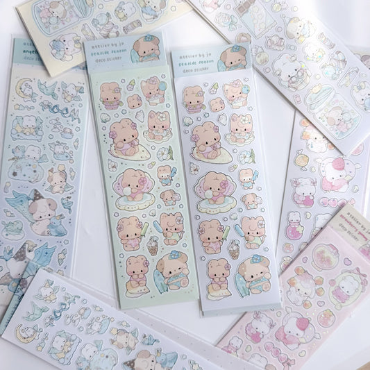 A flat lay of multiple sheets of cute cartoon bear stickers on pastel-colored backing papers, arranged on a white surface.