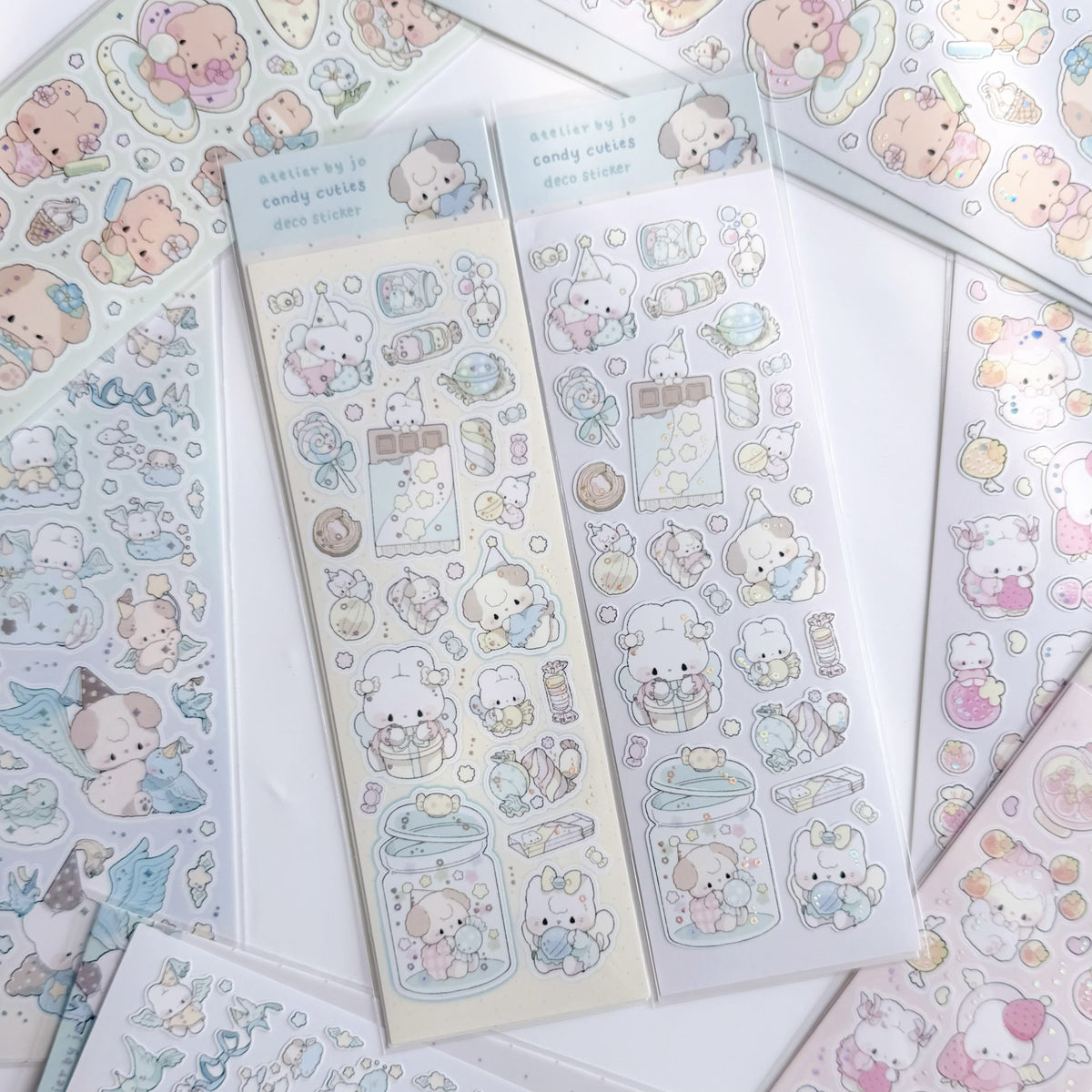 Several sheets of cute pastel stickers featuring a small bear character in different activities, arranged on a white background. The stickers are decorated with soft pastel colors including pinks, blues, yellows, and browns, and some sheets are still in their clear plastic packaging.