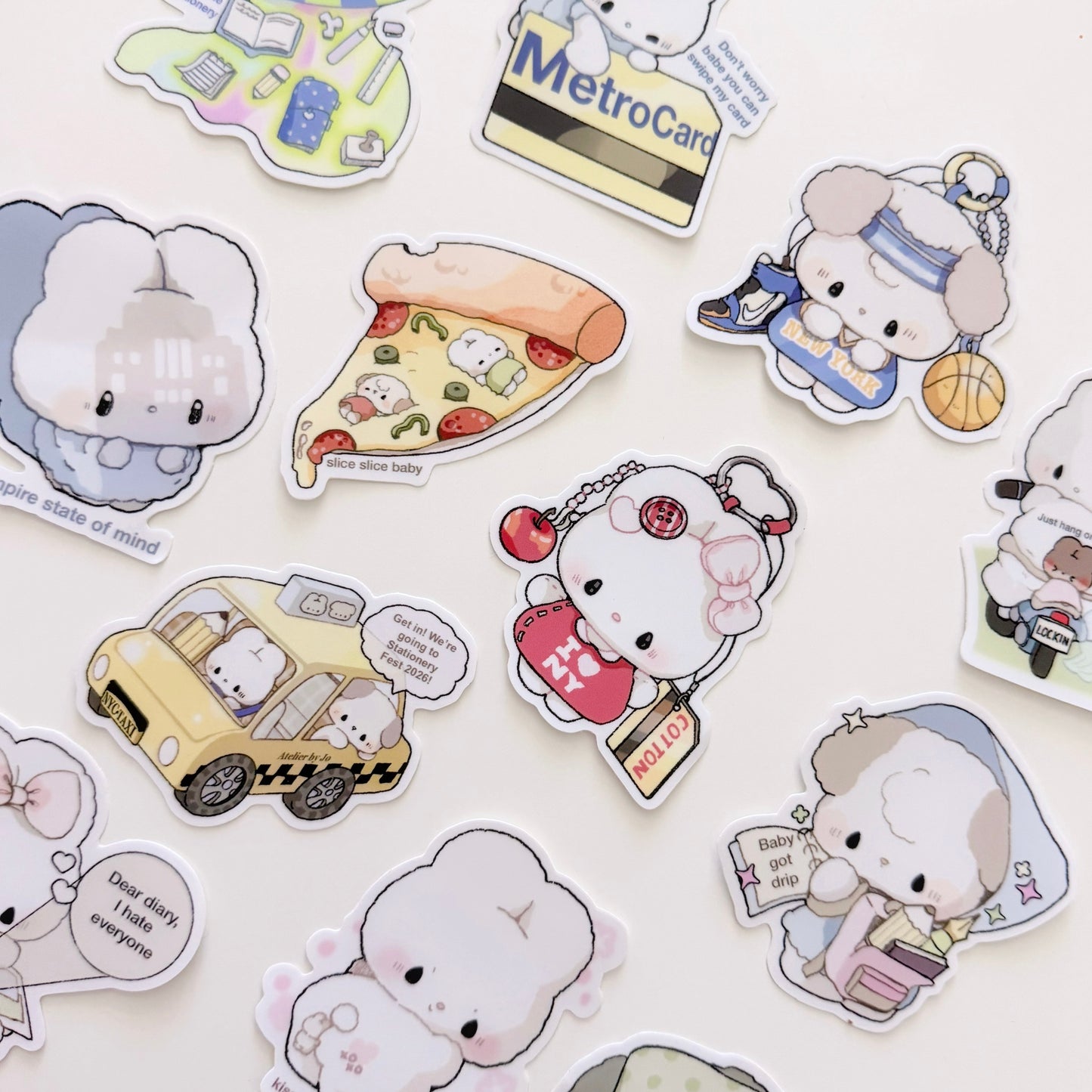 A collection of cute cartoon character stickers scattered on a light background. The characters include a white fluffy bunny in a gray hoodie, a slice of pizza with small food characters, a yellow taxi cab with a driver, a white cat in a red apron holding a shopping bag, and other playful illustrated scenes.