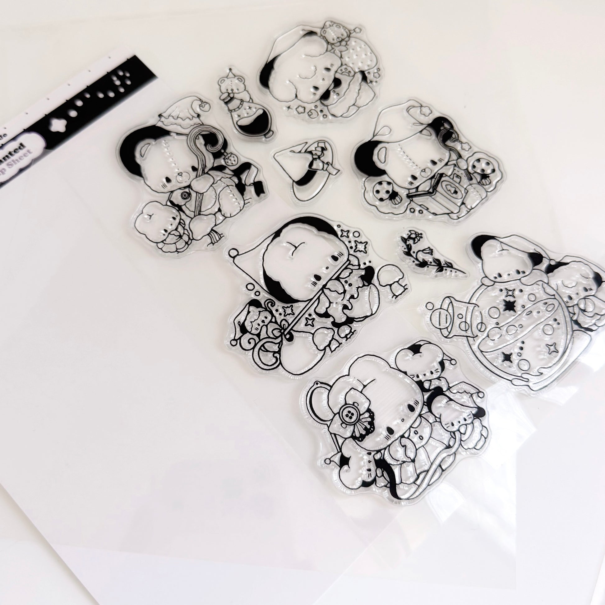 A flatlay sheet of silicone stamps featuring bear and rabbit wearing pointy hats on a white background
