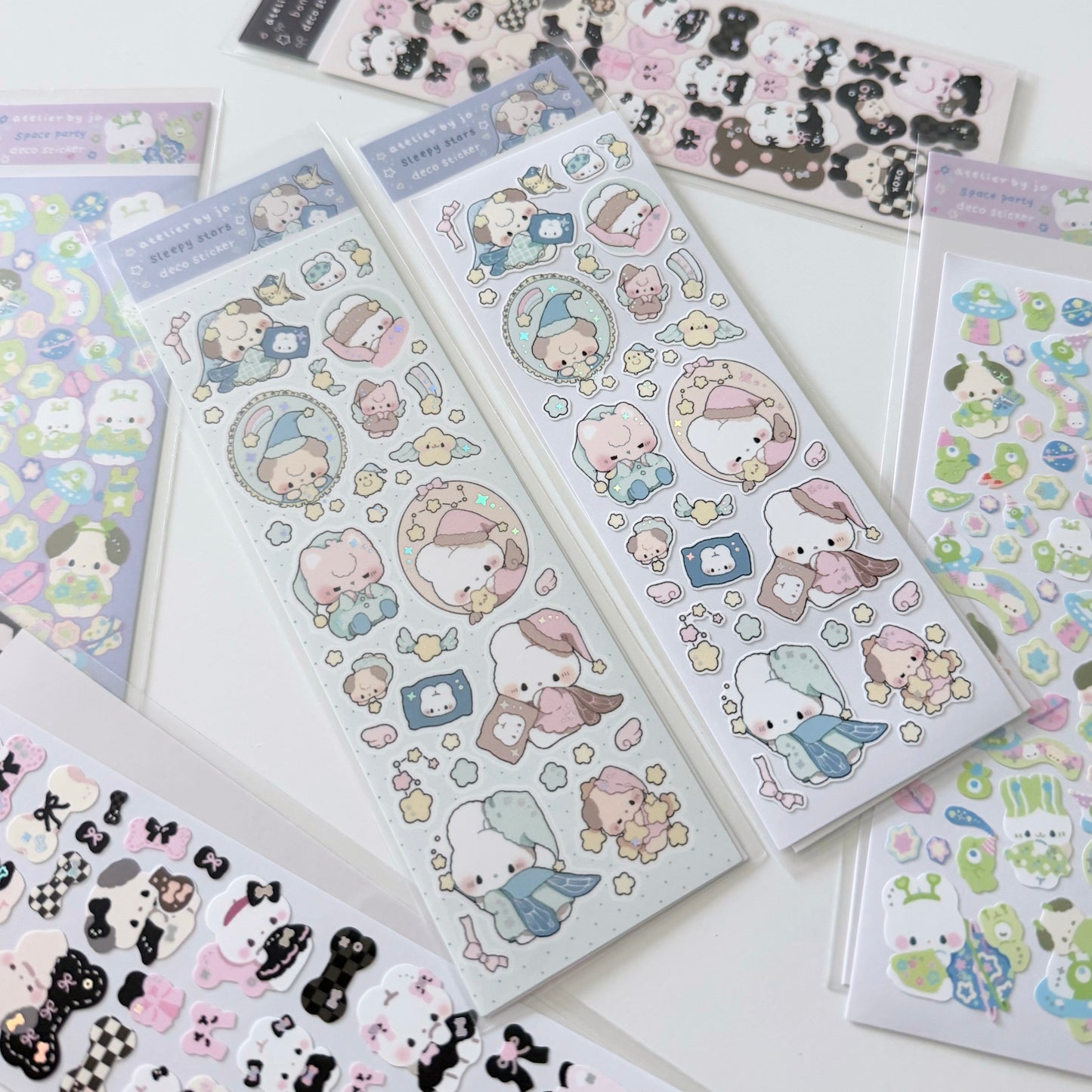 Several sheets of cute cartoon stickers arranged on a white surface. The stickers feature pastel-colored characters in round hats and scarves, with small stars, hearts, and decorative elements.