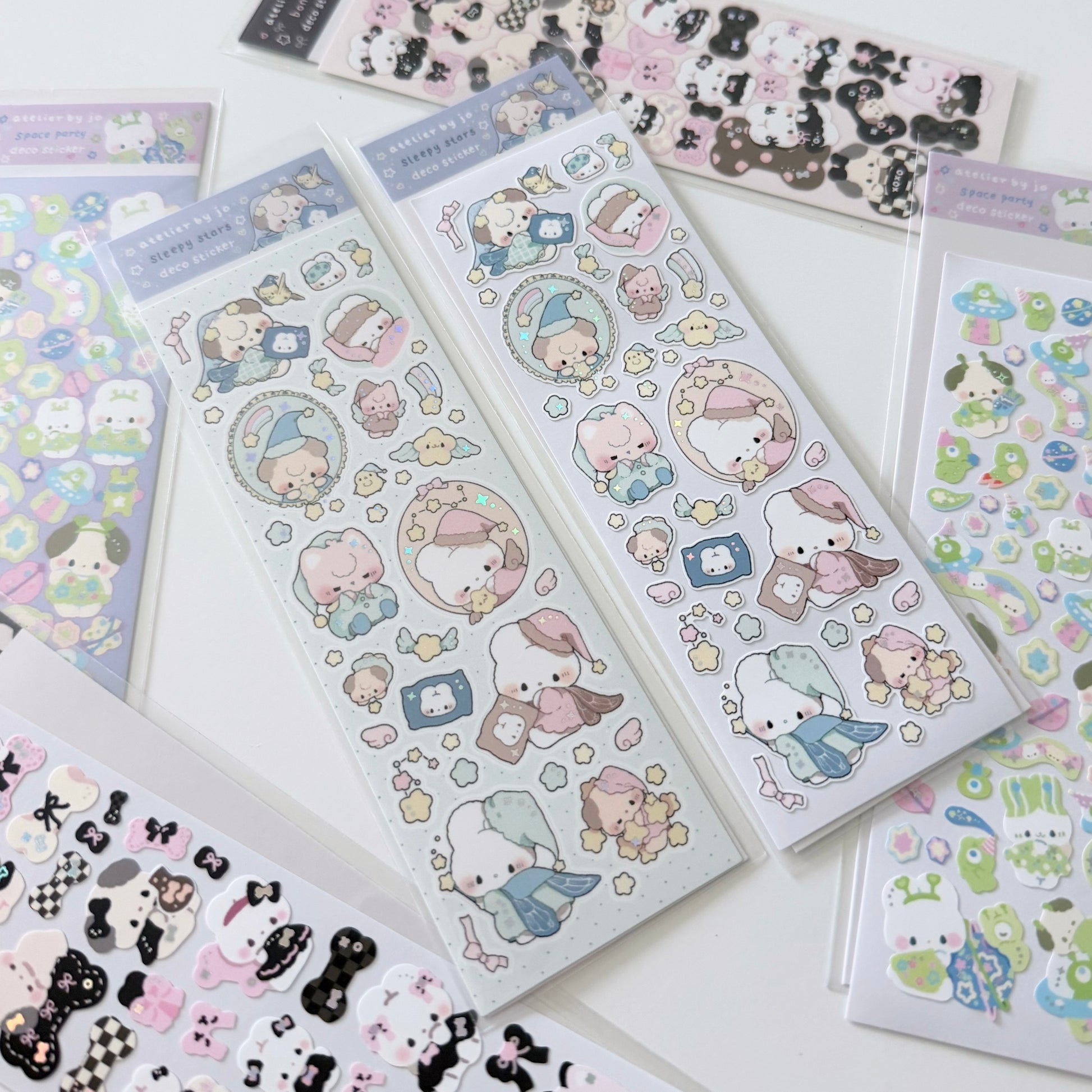 Several sheets of cute cartoon stickers arranged on a white surface. The stickers feature pastel-colored characters in round hats and scarves, with small stars, hearts, and decorative elements.