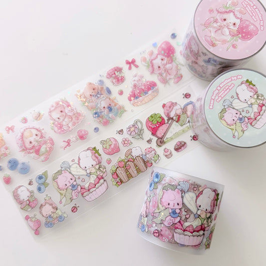A set of cute pastel washi tape products on a clean white background, including a long unrolled strip and three rolled tubes. The designs feature cartoon characters, strawberries, cupcakes, and small decorative motifs in soft pink, blue, and green tones.