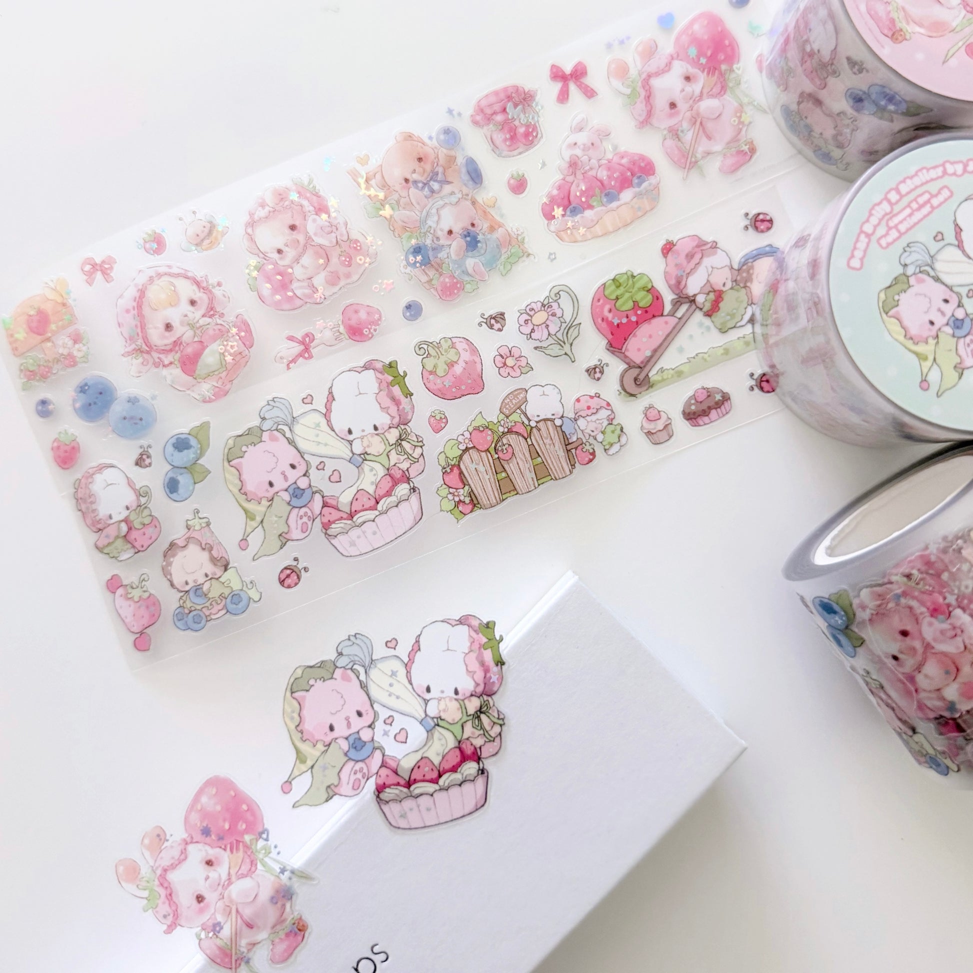 A set of cute pastel washi tape rolls and sheets featuring a cartoon bunny and strawberry-themed illustrations, arranged on a white surface.